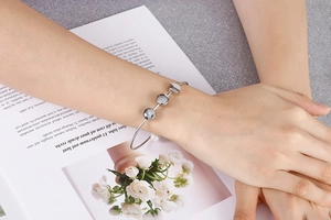 Close-up of polished silver stainless steel cuff bracelet with three beads on wrist