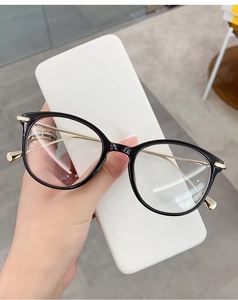 Detailed view of cat-eye glasses frame featuring black rims and golden metal temples