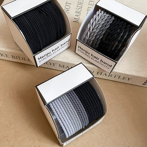 Gros plan d'élastiques à cheveux tressés haute élasticité en gris et noir sur des livres