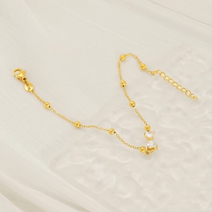 Elegant gold stainless steel bracelet with heart-shaped zircon pendants on white silk background