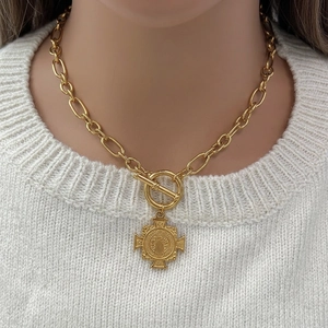 Thick OT toggle gold-plated cross medallion necklace on a white sweater background