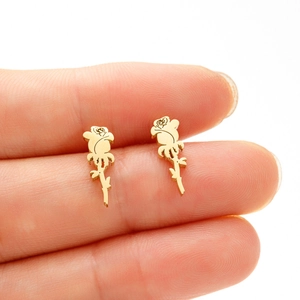 Macro shot of minimalist gold rose stud earrings held between fingers for size reference