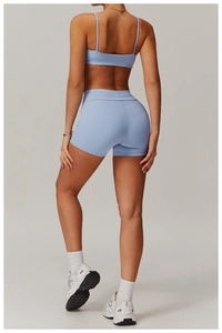 Detail eines hellblauen Sport-BHs mit überkreuztem Rücken und High-Waist-Shorts am Model