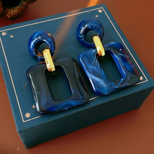 Detailed view of dark blue marble resin square earrings with gold accents on a gift box