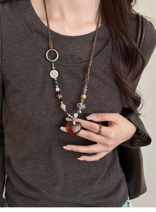Close-up of vintage beaded necklace featuring a red heart pendant on a brown leather cord
