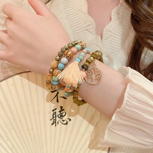 Detail of layered bohemian sandalwood beads with rose charms and peach silk tassel