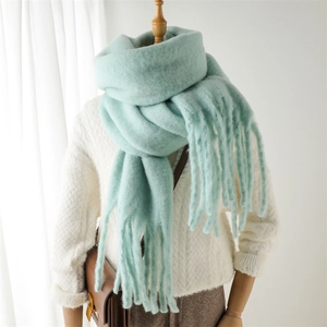 Texture détaillée de l'écharpe épaisse en mohair vert menthe avec pompons sur un mannequin