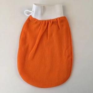 Detail of orange exfoliating bath glove with coarse texture and white elastic cuff