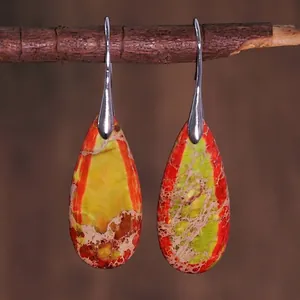 Close-up of teardrop emperor stone earrings with colorful textures on a branch