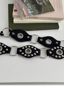 Detail of Y2K punk PU leather belt with silver metal rings and studded rivet design