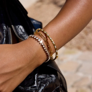 Set di tre bracciali con pietre tennis e ciondolo a cuore dorato indossato al polso