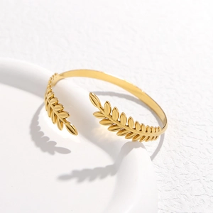 Dettaglio macro del motivo foglia di grano dorata su un bracciale in acciaio inossidabile