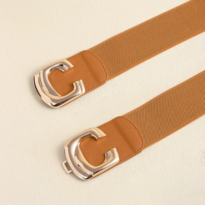 Detailed view of the elastic waist belt featuring a large polished golden C-shaped buckle