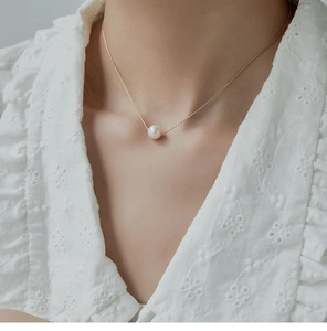 Close-up of a minimalist single pearl pendant necklace on a refined 18K gold-plated chain
