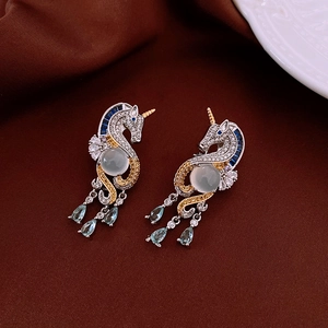 Detailed close-up of unicorn earrings with green center stone and blue teardrop charms