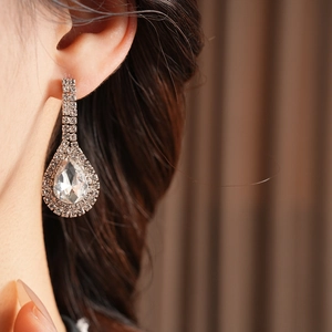 Close-up of elegant silver drop earrings with clear zircons on a female model's ear