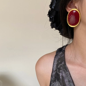 Close-up of vintage oval burgundy earrings with matte gold frames on a model ear