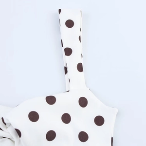 Détail de la robe blanche à pois noirs montrant l'encolure et les coutures de bretelles