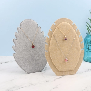 Velvet necklace display stand set with jewelry on marble surface and blue backdrop