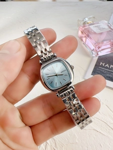 Detail of elegant silver steel watch featuring a sky blue square dial and 5-link band