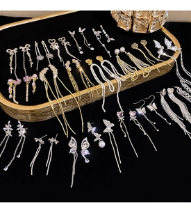 Detailed close-up of crystal bow tassel earrings on black velvet and gold jewelry trays