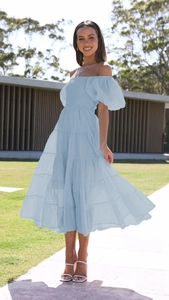 Close-up of light blue off-shoulder dress featuring puff sleeves and tiered skirt detail