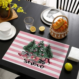 Detail of pink striped Christmas placemat featuring festive trees and Snow lettering