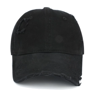 Detail of distressed black cotton baseball cap showing vintage frayed holes and texture