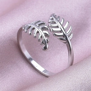 Macro close-up of a silver leaf-shaped open ring on pink silk background