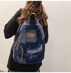 Detail of a denim patchwork backpack with brown leather accents and top handle