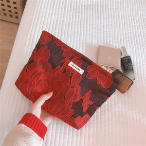 Close-up of floral embossed fabric cosmetic bag with red rose embroidery detail