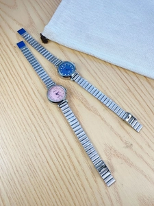 Close-up of pink and blue dial ladies watches with silver steel bands on wooden desk
