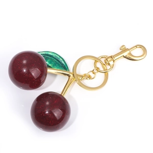 Macro detail of cherry keychain with deep red glitter resin balls and golden clasp