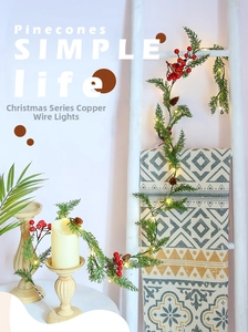 Detail of warm white copper string lights with artificial pinecones and red berries