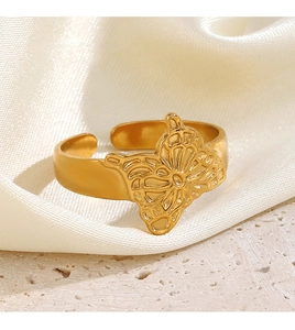 Detail of a golden openwork butterfly ring on silk and stone background