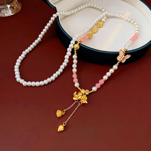 Lotus and butterfly pearl necklace with gold tassel on a deep green jewelry box