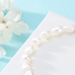 Elegant white baroque freshwater pearl bracelet on a minimalist textured background