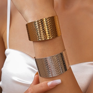 Detail view of gold and silver chunky cuff bracelets with hammered texture on a model