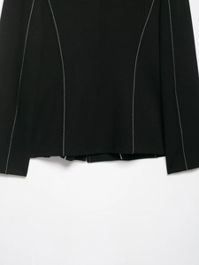 Close-up of contrast white stitching details on the hem of a black blazer and skort set