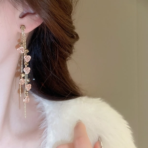 Détail de boucles d'oreilles pendantes rose et cristaux sur mannequin pour style chic