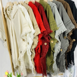 Detailed knit texture and decorative buttons on a Bohemian tassel shawl poncho sweater