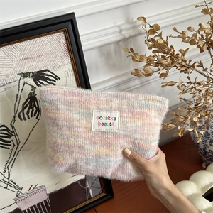 Close-up of rainbow plush makeup bag with soft mohair texture and branded label detail