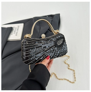 Detail of black sequined clutch with gold handle, chain strap, and rhinestone clasp