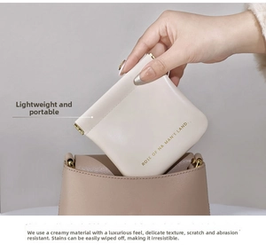 Creamy white faux leather mini pouch with squeeze closure shown inside a larger brown bag
