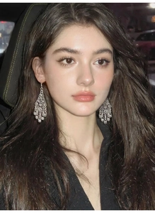 Silver hollow flower teardrop tassel earrings worn by a model in a luxury car setting