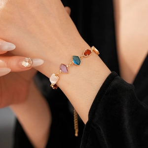 Détail d'un bracelet vintage en nacre dorée serti de pierres précieuses colorées