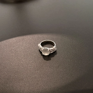 Close-up of S925 sterling silver ring with oval white gemstone and pavé diamonds