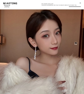 Close-up of elegant long tassel rhinestone earrings on model wearing white fur