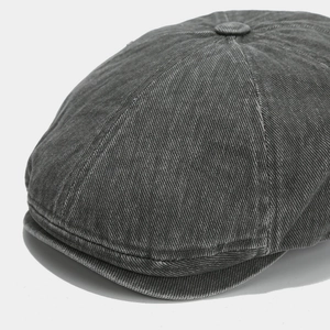 Macro shot of dark grey washed denim newsboy cap with detailed twill texture and button top