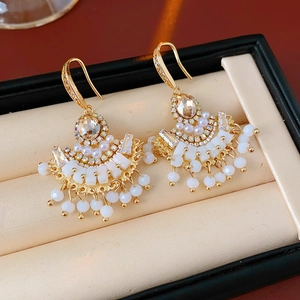 Détails de boucles d'oreilles dorées en éventail avec perles et glands de perles